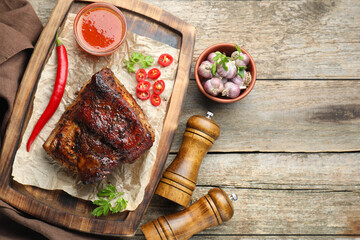 Piece of baked pork belly served with sauce and chili pepper on wooden table, flat lay. Space for...