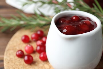 Fresh cranberry sauce in pitcher on table, closeup. Space for text