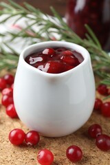 Cranberry sauce in pitcher and fresh berries on board, closeup