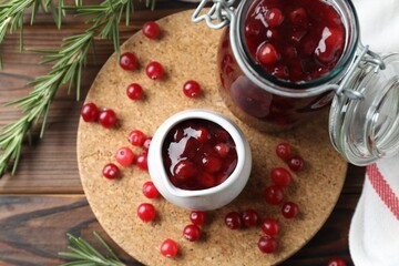 Cranberry sauce, fresh berries and rosemary on wooden table, flat lay