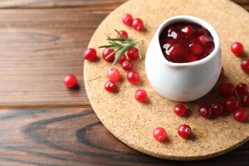 Cranberry sauce, fresh berries and rosemary on wooden table, space for text