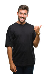 Young handsome man over isolated background smiling with happy face looking and pointing to the side with thumb up.