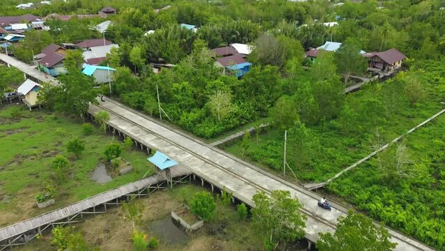 Flying drones show people riding motorbikes on the boards of the Agats Asmat city of Papua