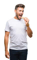 Young handsome man eating chocolate chips cookie over isolated background with a confident...