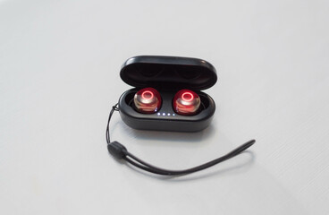 Black wireless earbuds inside power bank case on white background. 