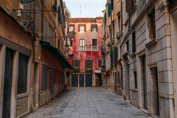 Lonely path way along the Venetian city with high facades and mystic shadows