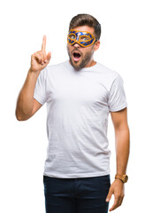 Young handsome man wearing carnival mask over isolated background pointing finger up with...