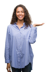 Young hispanic business woman smiling cheerful presenting and pointing with palm of hand looking at the camera.