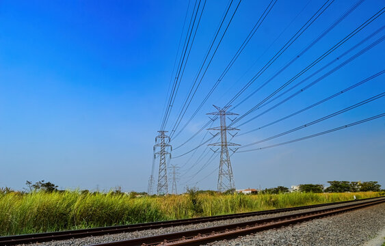 two towers of high-voltage electricity poles that cross over the double-track railroad tracks