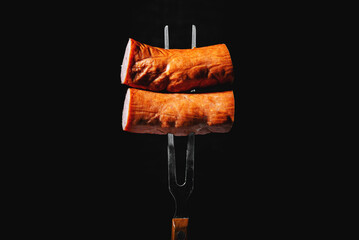 sausage on a fork on a black background
