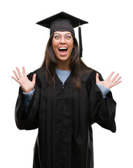 Young hispanic woman wearing graduated cap and uniform celebrating crazy and amazed for success...