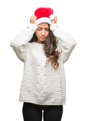 Young arab woman wearing christmas hat over isolated background suffering from headache desperate and stressed because pain and migraine. Hands on head.