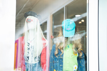 View through the glass of a mannequin in colorful fashion clothes in a clothing store. Fashion model. Colorful holiday concept