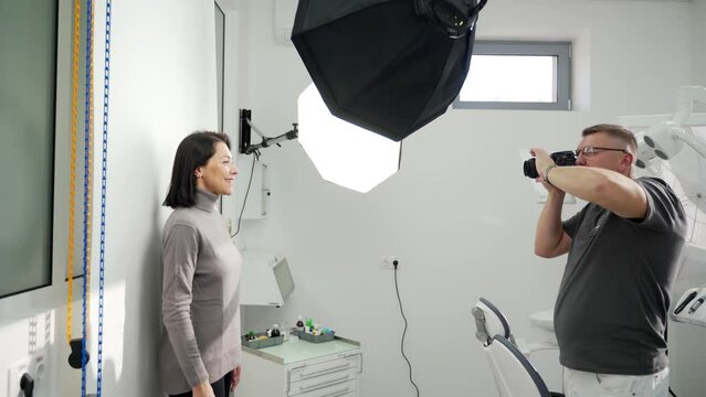 Male dentist photographing woman before modeling the veneers in modern dental office with the lighting equipment. Taking photo of female patient before UV whitening procedure. Cosmetic dentistry.