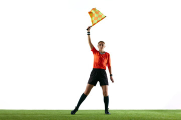 Stopping game. Young woman, soccer referee raising flag up meaning ball is out-of-play and game need restart against white background. Concept of sport, competition, match, profession, football game - obrazy, fototapety, plakaty