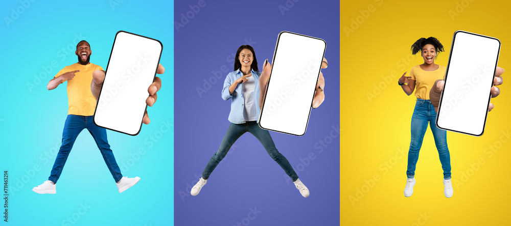 Poster joyful multiethnic people jumping and pointing at big blank smartphone in hands