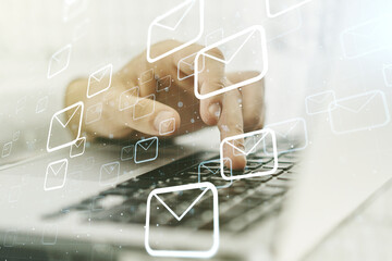 Double exposure of postal envelopes hologram with hands typing on laptop on background. Electronic...