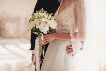 Bride holding a beautiful white wedding bouquet. Sensual wedding couple.Romantic moments of...