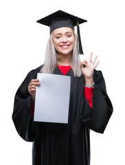 Young blonde woman wearing graduate uniform holding degree over isolated background doing ok sign with fingers, excellent symbol
