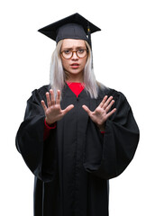 Young blonde woman wearing graduate uniform over isolated background afraid and terrified with fear expression stop gesture with hands, shouting in shock. Panic concept.