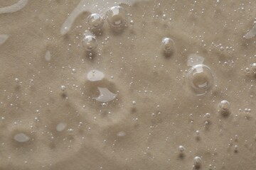 Clear cosmetic serum on beige background, macro view