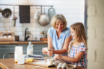 Grandmother and granddaughter cooking together in kitchen