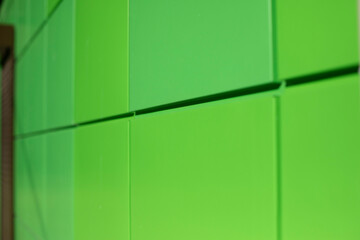 Green metal wall. Square wall slabs. Exterior of building.
