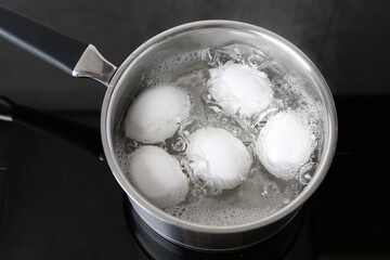 Chicken eggs boiling in saucepan on electric stove, above view