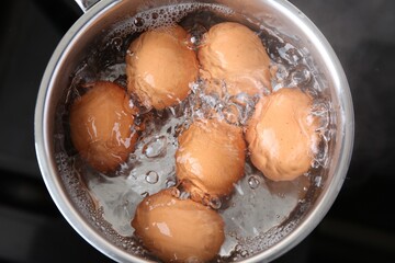 Chicken eggs boiling in saucepan on electric stove, top view