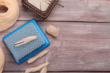 Felting tools and wool on wooden table, flat lay. Space for text