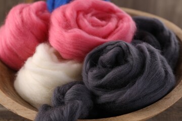 Fototapeta na wymiar Colorful felting wool in bowl on table, closeup