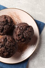 Delicious chocolate muffins and cacao powder on light grey table, top view
