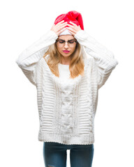 Young beautiful blonde woman wearing christmas hat over isolated background suffering from headache desperate and stressed because pain and migraine. Hands on head.