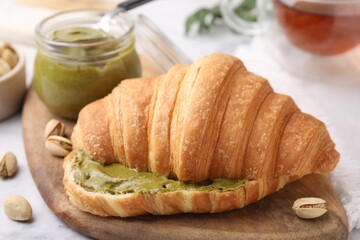 Croissant with tasty pistachio cream and nuts on table, closeup