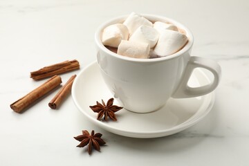 Tasty hot chocolate with marshmallows and spices on white marble table, closeup