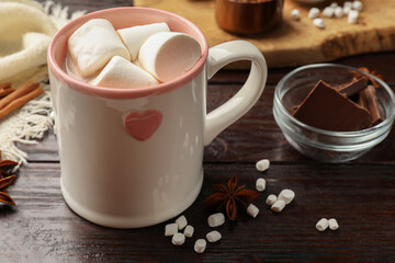 Tasty hot chocolate with marshmallows and ingredients on wooden table, closeup