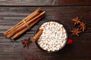Tasty hot chocolate with marshmallows and spices on wooden table, flat lay