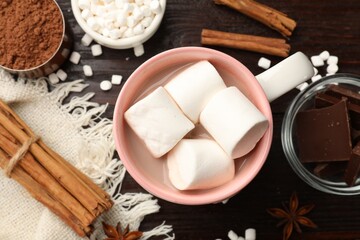 Tasty hot chocolate with marshmallows and ingredients on wooden table, flat lay