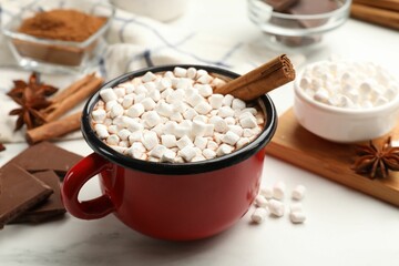 Tasty hot chocolate with marshmallows and ingredients on white marble table, closeup