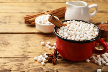 Tasty hot chocolate with marshmallows and ingredients on wooden table, closeup. Space for text