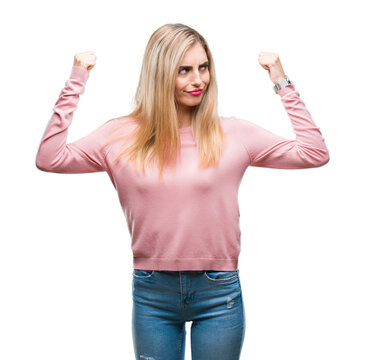Young beautiful blonde woman wearing pink winter sweater over isolated background showing arms muscles smiling proud. Fitness concept.