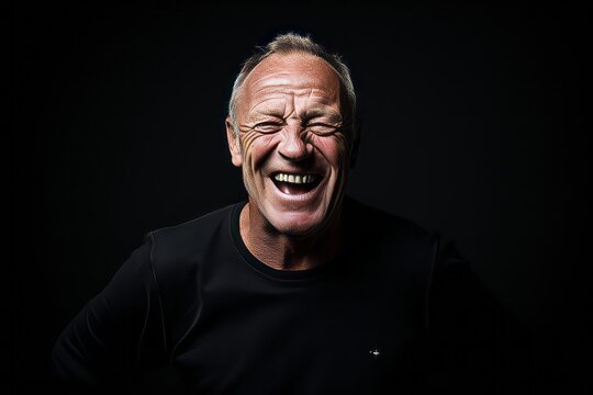 Portrait of a senior man screaming in pain on a black background.