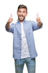 Young handsome man wearing white t-shirt over isolated background approving doing positive gesture with hand, thumbs up smiling and happy for success. Looking at the camera, winner gesture.