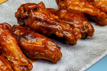 Plate of barbecued chicken wings on a yellow and light blue gradient background