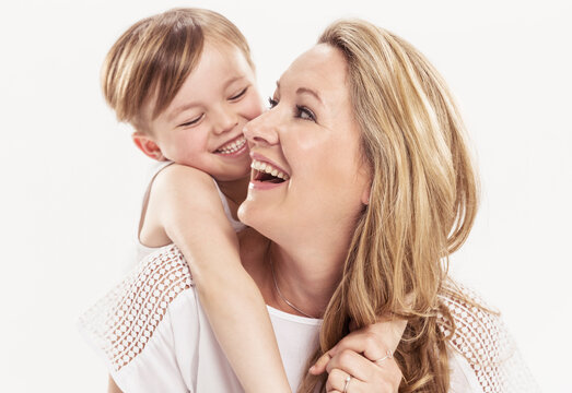 Studioportrait Mutter Kind barfuss in Jeans die sich gegenseitig anlachen