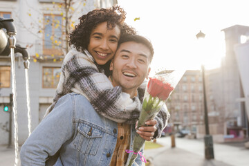 young couple enjoy the sunset in the city for valentine's day while the boyfriend carries his...