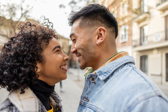 portrait young multiethnic couple in love looking into each other's eyes while smiling