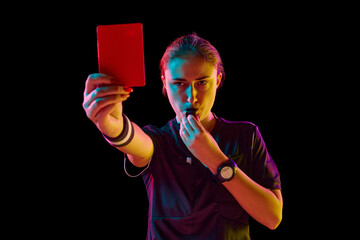 Young concentrated woman, soccer referee blowing a whistle and showing red card as dismissal symbol...