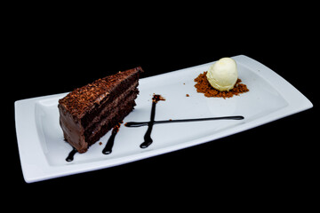 Chocolate cake on a white plate with ice cream on a black  background