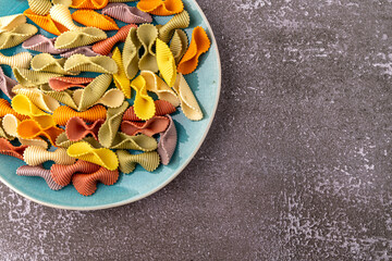 Colorful pasta background. Top view of five colors pasta shells .Heap of colorful spiral...